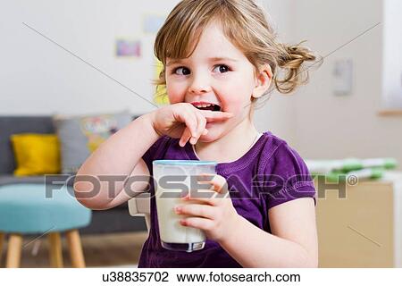 Girl holding glass of milk at home View Large Photo Image Stock Image - Girl holding glass of milk at home. Fotosearch