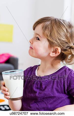 Girl holding glass of milk at home View Large Photo Image Stock Photo - Girl holding glass of milk at home. Fotosearch