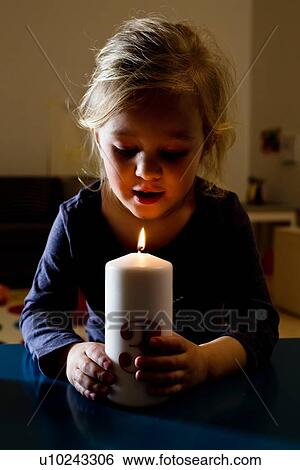 Girl holding lit candle in dark View Large Photo Image Stock Photograph - Girl holding lit candle in dark. Fotosearch