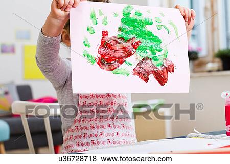 Girl holding up painting at home View Large Photo Image Stock Photo - Girl holding up painting at home. Fotosearch