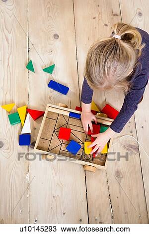 Stock Image - Girl playing with building blocks at home. Fotosearch