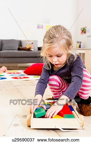 Stock Photo - Girl playing with building blocks at home. Fotosearch