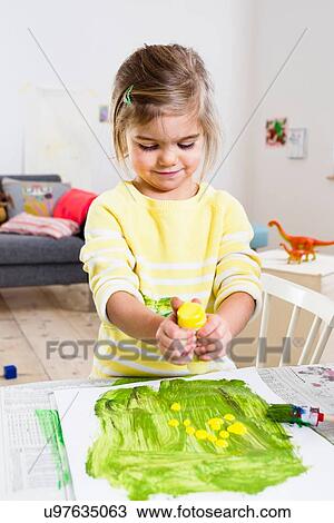 Stock Image - Girl playing with paint at home. Fotosearch