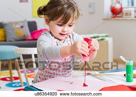 Girl pouring paint on paper at home View Large Photo Image Stock Image - Girl pouring paint on paper at home. Fotosearch