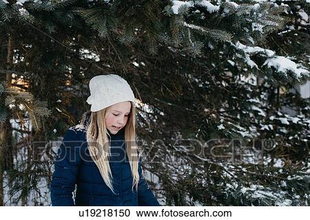 Stock Image - Girl standing by fir tree. Fotosearch