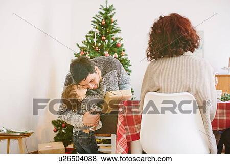 Girl thanking father for gift at family Christmas party View Large Photo Image Stock Photo - Girl thanking father for gift at family Christmas party. Fotosearch