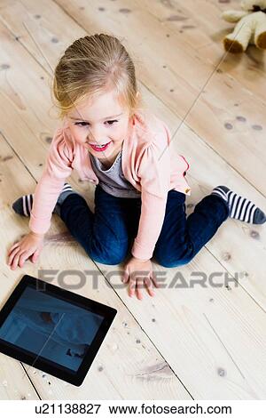 Girl using digital tablet on wooden floor View Large Photo Image Stock Photo - Girl using digital tablet on wooden floor. Fotosearch
