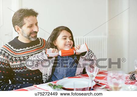 Stock Photo - Girl with Christmas cracker at family Christmas party. Fotosearch
