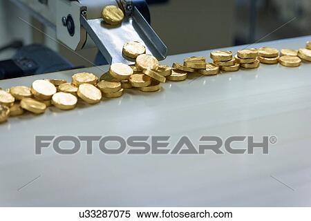 Stock Photography - Gold wrapped chocolates on production line in chocolate factory. Fotosearch