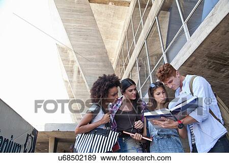 Group of students looking at book View Large Photo Image Stock Photo - Group of students looking at book. Fotosearch