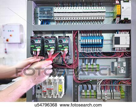 Stock Photo - Hands of electrical engineer testing switch board in engineering factory. Fotosearch