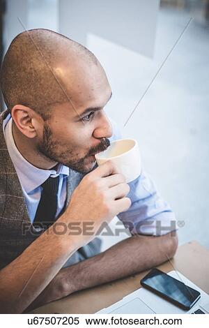 High angle view of businessman sitting in cafe drinking coffee View Large Photo Image Stock Photography - High angle view of businessman sitting in cafe drinking coffee. Fotosearch