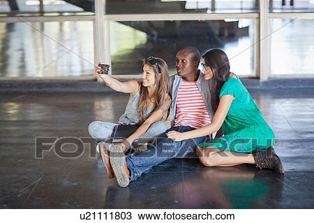 Higher education students sitting on floor using cameraphone View Large Photo Image Stock Image - Higher education students sitting on floor using cameraphone. Fotosearch