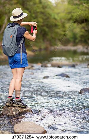 Picture - "Hiker taking photograph, Waima Forest, North Island, NZ". Fotosearch