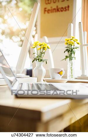 Stock Photo - Laptop on table in cafe with coffee cup beside it. Fotosearch
