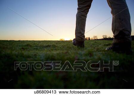 Legs of male hiker walking over field at sunset View Large Photo Image Stock Image - Legs of male hiker walking over field at sunset. Fotosearch