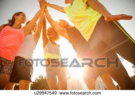 Low angle view of adult friends giving high five in park View Large Photo Image Stock Photo - Low angle view of adult friends giving high five in park. Fotosearch