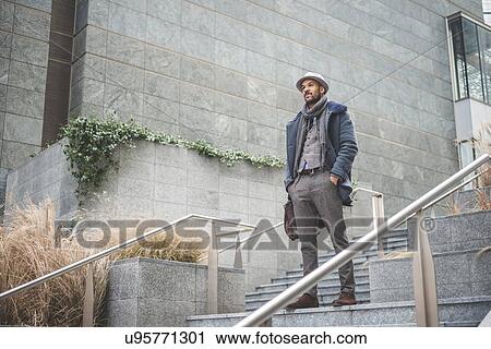 Stock Image - Low angle view of confident mid adult businessman standing on stairway. Fotosearch