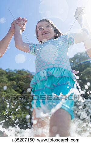 "Low angle view of girl holding hands and running in sea, Hot Water Beach, Bay of Islands, New Zealand" View Large Photo Image Stock Image - "Low angle view of girl holding hands and running in sea, Hot Water Beach, Bay of Islands, New Zealand". Fotosearch