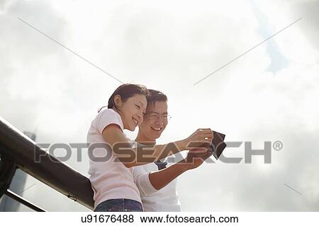 "Low angle view of tourist couple looking at instant film photographs, The Bund, Shanghai, China" View Large Photo Image Stock Photo - "Low angle view of tourist couple looking at instant film photographs, The Bund, Shanghai, China". Fotosearch