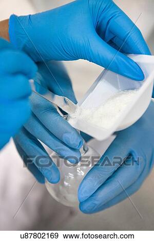 Stock Photo - Male and female gloved hands transferring powder into laboratory flask. Fotosearch
