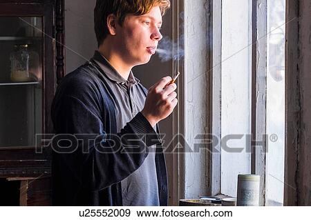 Male artist smoking cigarette whist staring out of studio window View Large Photo Image Stock Photo - Male artist smoking cigarette whist staring out of studio window. Fotosearch