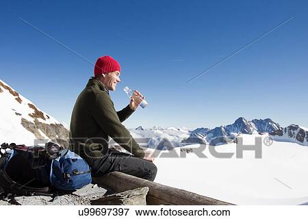 Stock Photo - "Male hiker drinking water on viewing platform, Jungfrauchjoch, Grindelwald, Switzerland". Fotosearch