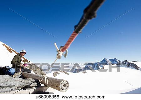 Stock Photography - "Male hiker eating snacks on viewing platform, Jungfrauchjoch, Grindelwald, Switzerland". Fotosearch