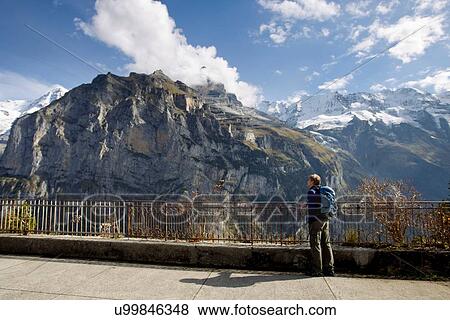 Stock Photo - "Male hiker gazing toward Nordwand of Mount Eiger, Murren, Grindelwald, Switzerland". Fotosearch