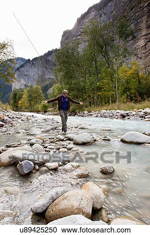 "Male hiker stepping over rocks in river, Grindelwald, Switzerland" View Large Photo Image Stock Image - "Male hiker stepping over rocks in river, Grindelwald, Switzerland". Fotosearch