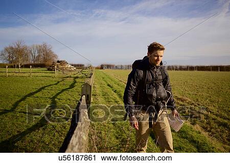 Stock Image - Male hiker walking in field. Fotosearch