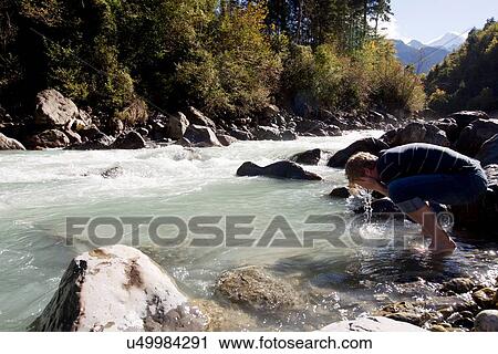 Stock Image - "Male hiker washing his face in river, Lauterbrunnen, Grindelwald, Switzerland". Fotosearch