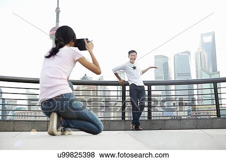 Stock Photo - "Male tourist posing for girlfriend with instant camera, The Bund, Shanghai, China". Fotosearch