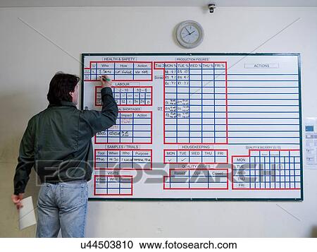 Male worker making notes on board in factory View Large Photo Image Stock Image - Male worker making notes on board in factory. Fotosearch