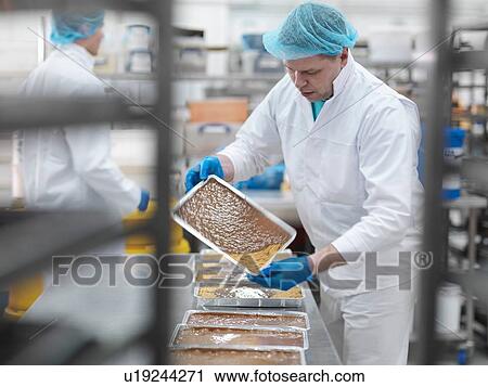 Stock Image - Male worker pouring chocolate in cake factory. Fotosearch