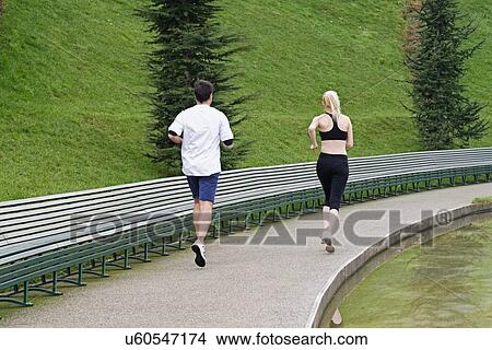 "Man and woman running beside lake, rear view" View Large Photo Image Picture - "Man and woman running beside lake, rear view". Fotosearch