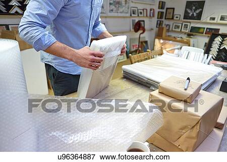Man bubble wrapping picture frame on table in picture framers workshop View Large Photo Image Stock Photo - Man bubble wrapping picture frame on table in picture framers workshop. Fotosearch