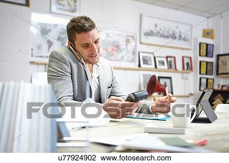 Man buying on smartphone with credit card reader in picture framers workshop View Large Photo Image Stock Image - Man buying on smartphone with credit card reader in picture framers workshop. Fotosearch