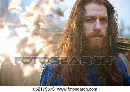 Stock Image - Man carrying bundle of wheat. Fotosearch