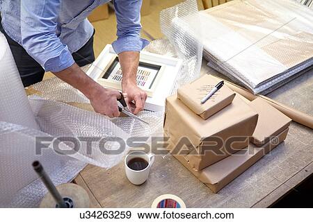 Man cutting bubble wrap on table in picture framers workshop View Large Photo Image Stock Photo - Man cutting bubble wrap on table in picture framers workshop. Fotosearch
