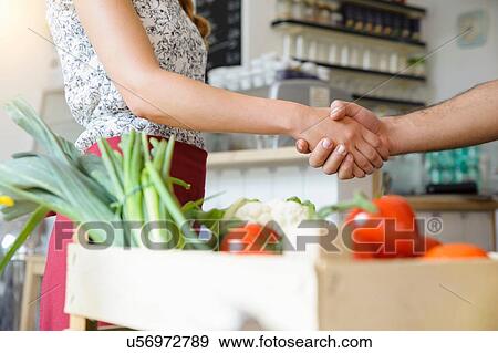 Stock Photo - Man delivering crate of vegetables to shopkeeper. Fotosearch