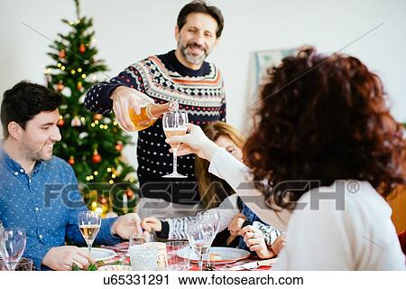 Man filling up glass at family Christmas party View Large Photo Image Stock Image - Man filling up glass at family Christmas party. Fotosearch
