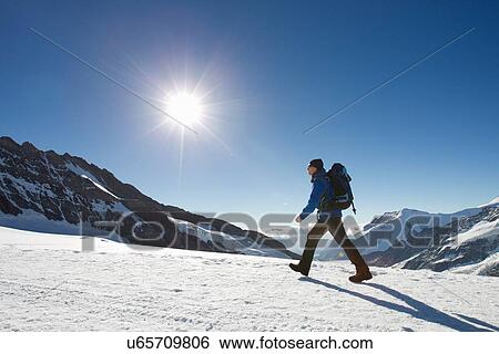 "Man hiking across snow covered mountain landscape, Jungfrauchjoch, Grindelwald, Switzerland" View Large Photo Image Stock Photograph - "Man hiking across snow covered mountain landscape, Jungfrauchjoch, Grindelwald, Switzerland". Fotosearch