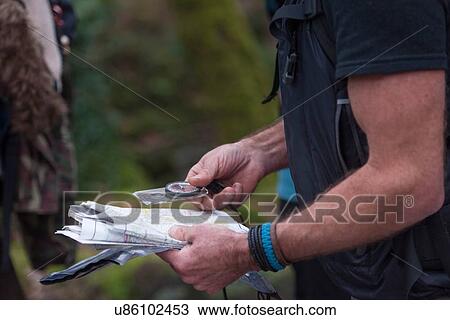 Stock Image - Man holding map and compass. Fotosearch