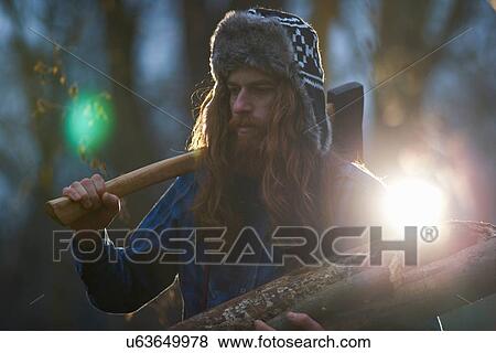 Man in trapper hat chopping wood in countryside View Large Photo Image Stock Photo - Man in trapper hat chopping wood in countryside. Fotosearch