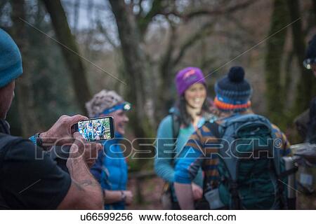 Stock Photograph - Man photographing friends with smartphone. Fotosearch