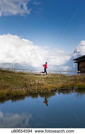 Picture - "Man running along lakeside, Kleine Scheidegg, Grindelwald, Switzerland". Fotosearch