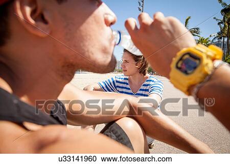 "Man sitting outdoors, drinking from water bottle, close-up" View Large Photo Image Stock Image - "Man sitting outdoors, drinking from water bottle, close-up". Fotosearch