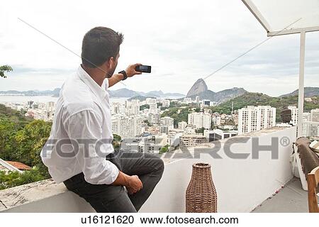 "Man taking photo on terrace, Sugarloaf Mountain in background, RIo, Brazil" View Large Photo Image Stock Image - "Man taking photo on terrace, Sugarloaf Mountain in background, RIo, Brazil". Fotosearch