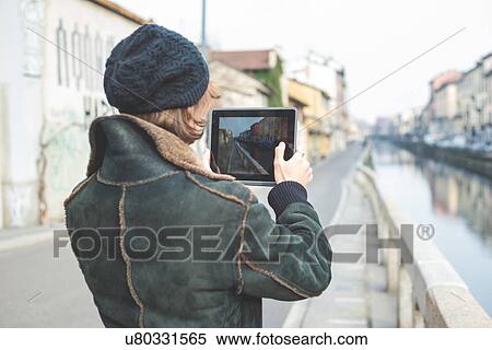 Stock Photography - "Man taking photograph of canal with digital tablet, Milan, Italy". Fotosearch